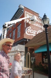 JORDAN MILES | HERALD Artist Jack Fralin, of Best Bet Arts, and The Shoppes at Poplar Hall Sales Manager Katy Anderson pause from watching second-generation Bill Johnson, above, give new pigment to the 20-foot by 20-foot Coca-Cola mural at Poplar Hall.